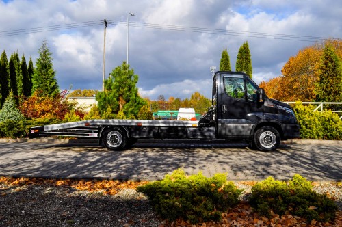 Czarna laweta Iveco Daily w jesiennej scenerii