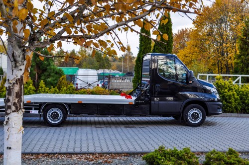 Czarna laweta Iveco Daily w jesiennej scenerii